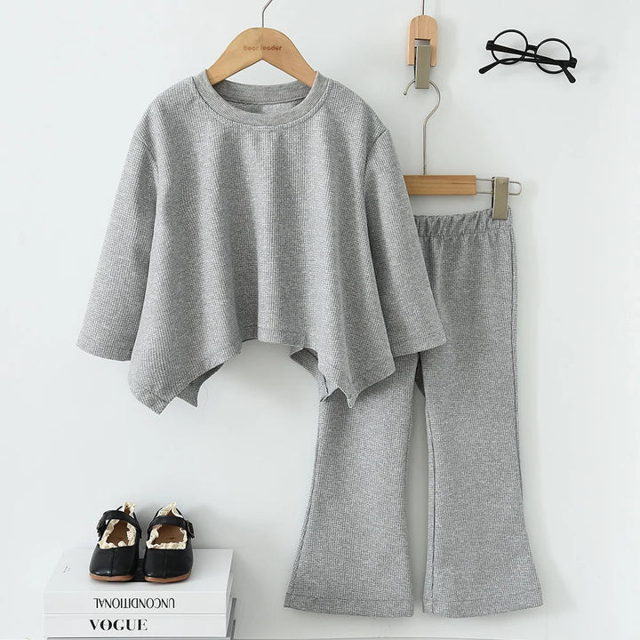 Gray outfit with top and pants on hangers against a white background