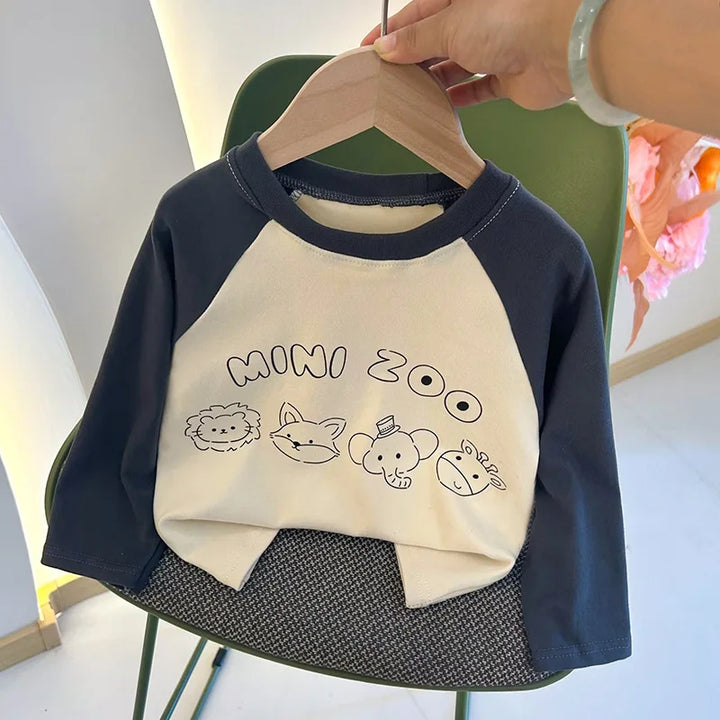 Children's sweatshirt with 'Mini Zoo' text and animal illustrations on a hanger.